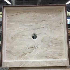 A marble shower stall with a hole in the middle is sitting on top of a wooden table.