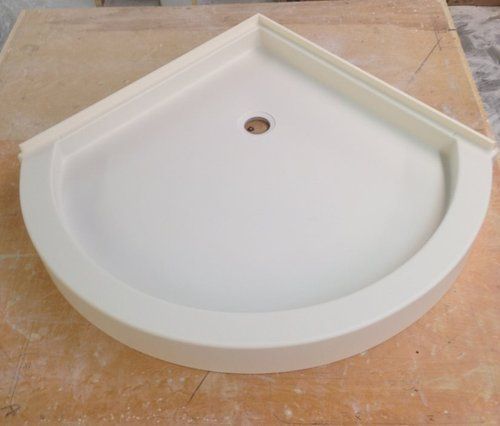 A white shower tray is sitting on top of a wooden table.