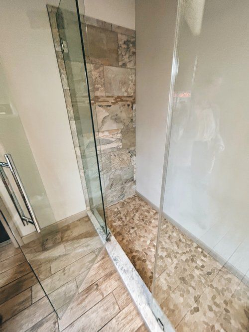 A bathroom with a walk in shower with a glass door.