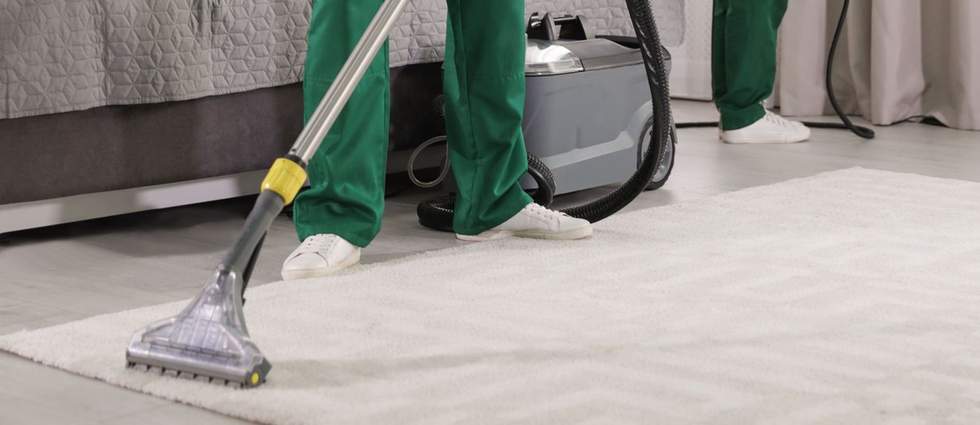 Person using a carpet cleaner to clean a white rug.