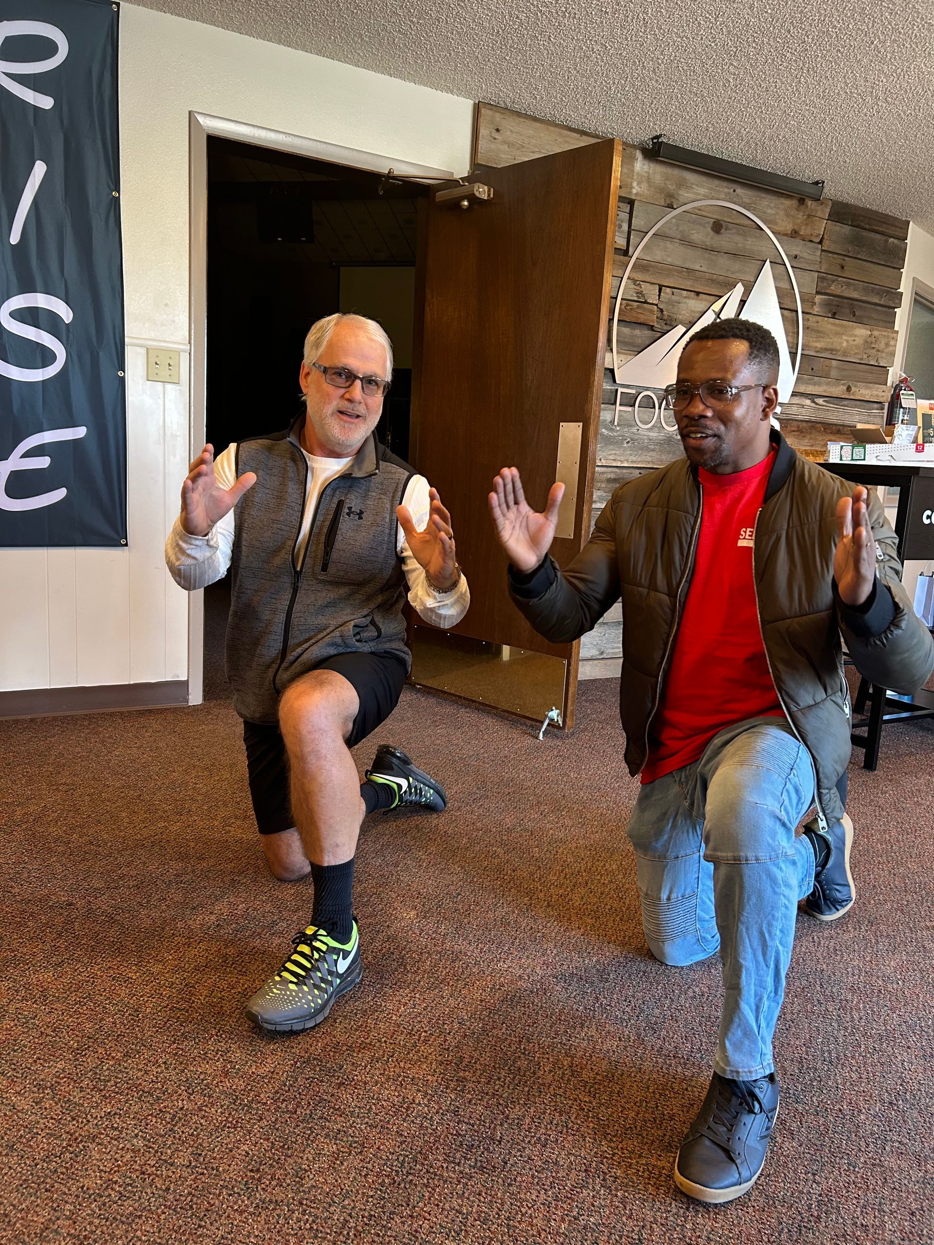 Two men are doing squats in a room
