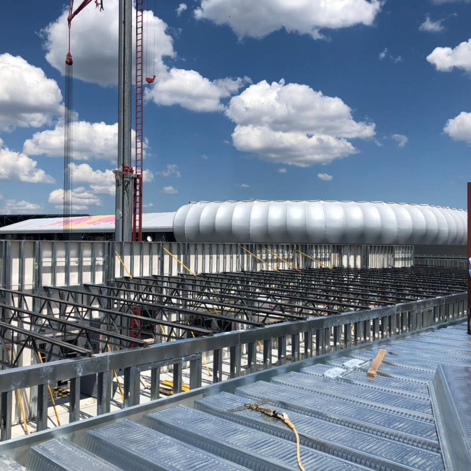A building under construction with a blue sky and clouds in the background