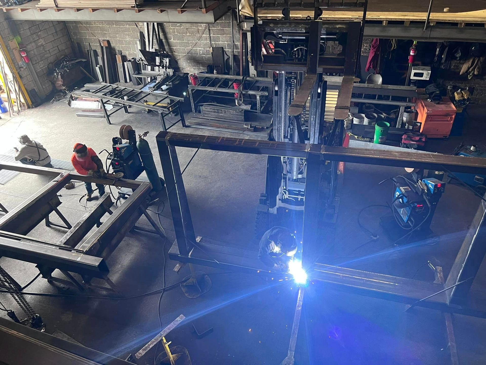 A group of people are welding a metal structure in a factory.