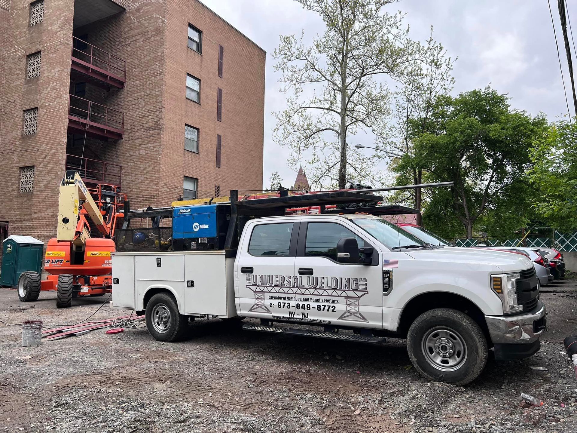 A white utility truck is parked in front of a brick building.