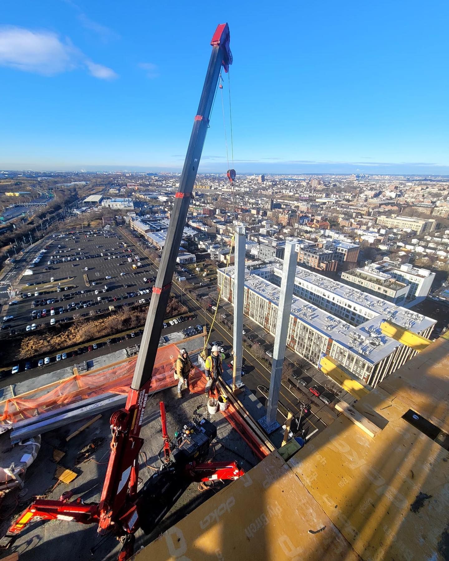 An aerial view of a construction site with a crane in the foreground and a city in the background.