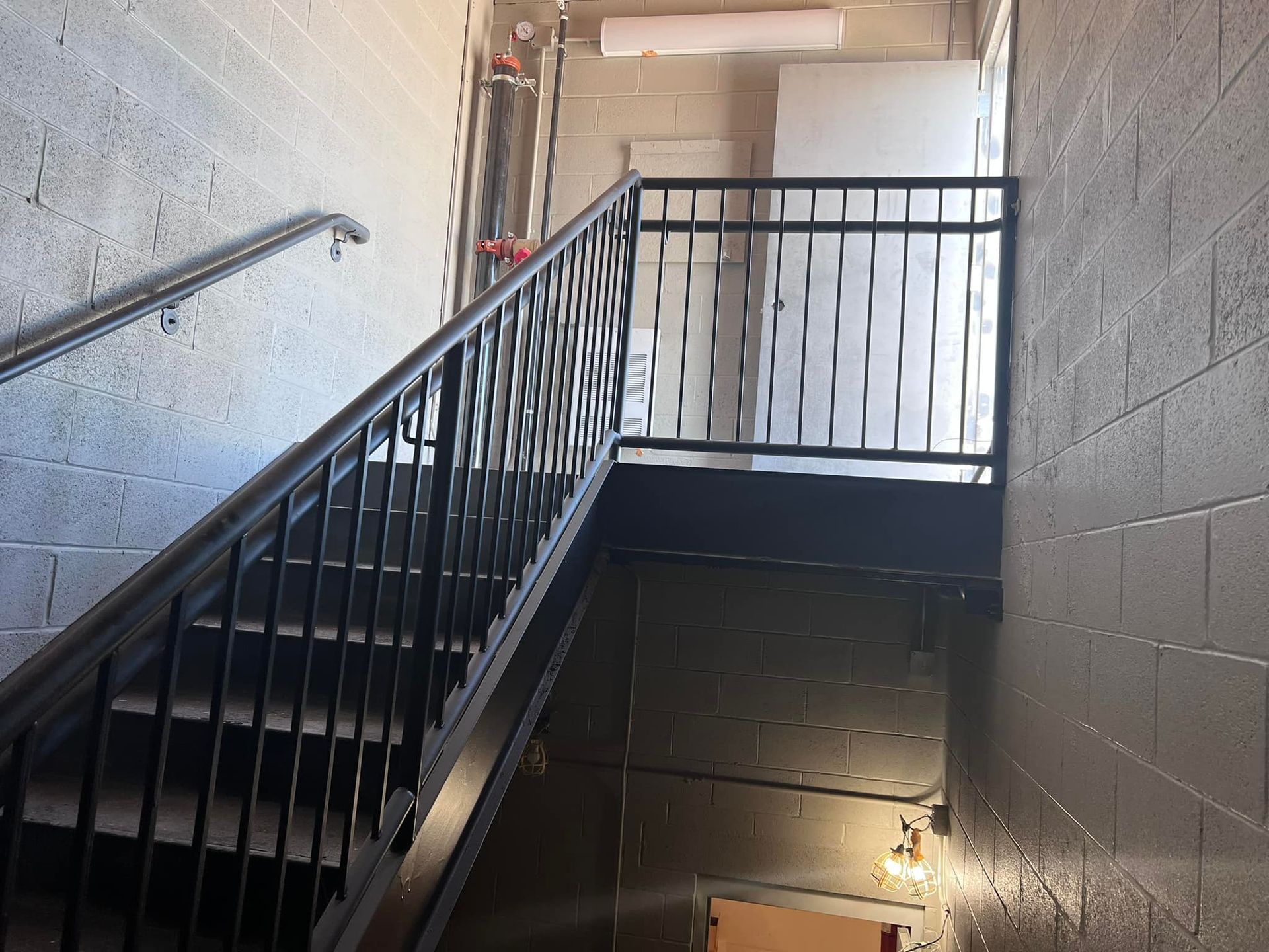 A staircase with a metal railing and a brick wall
