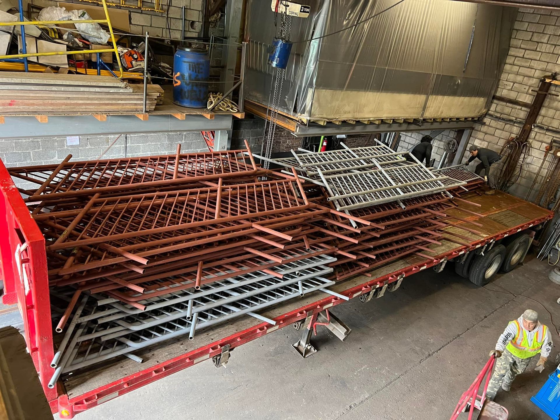 A red truck is carrying a stack of metal fences.