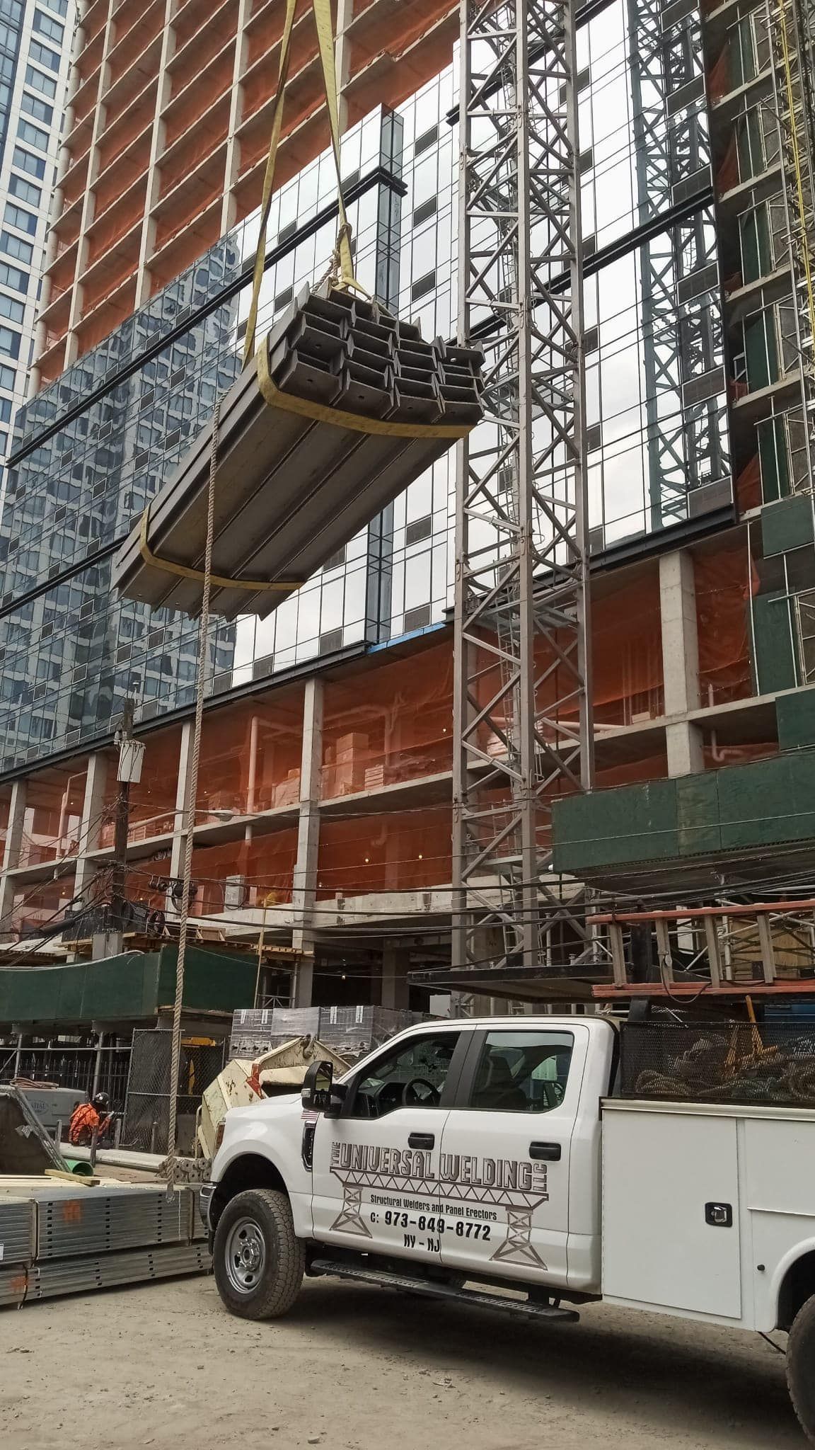 A white truck is parked in front of a building under construction.