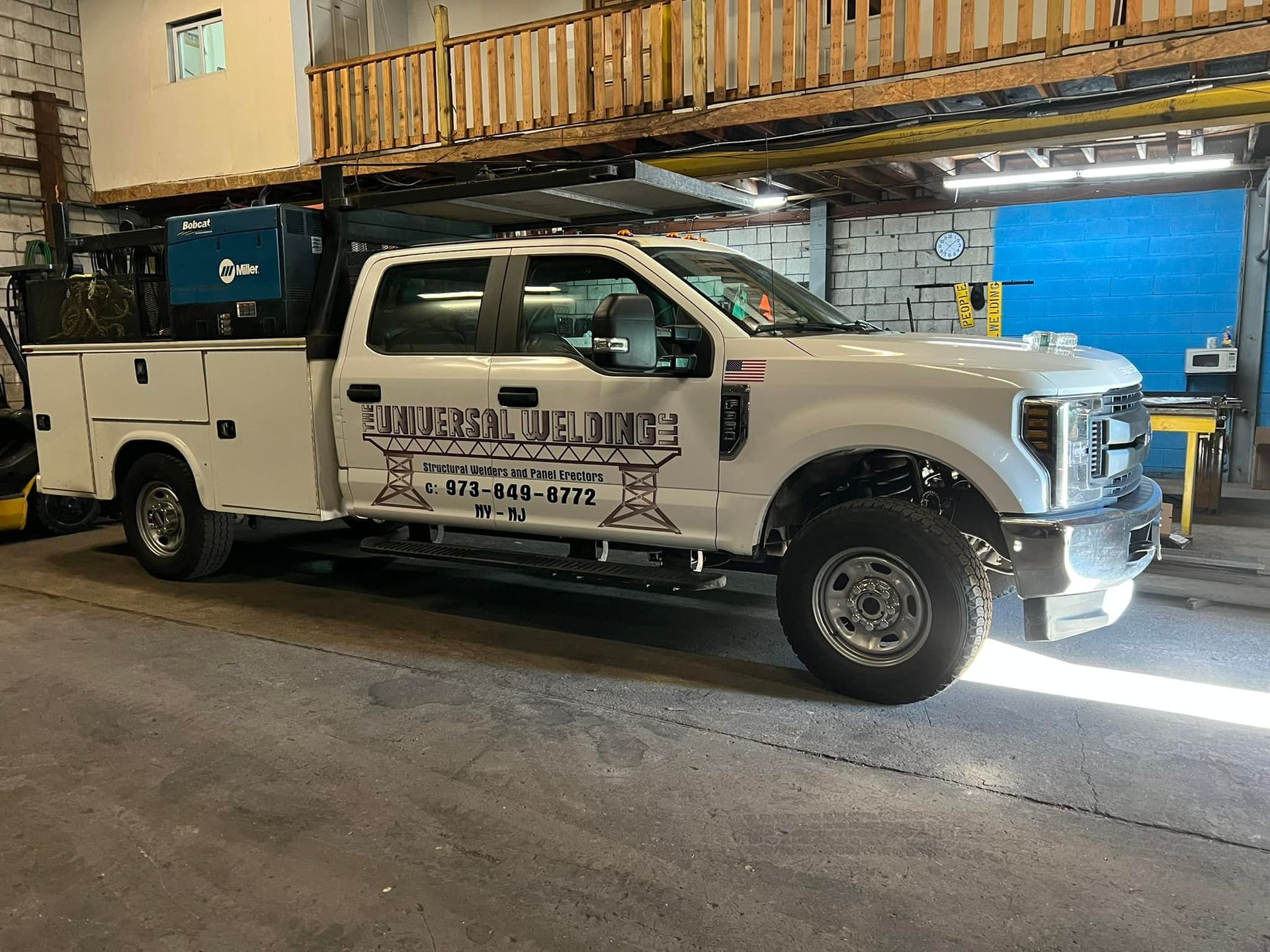 A white utility truck is parked in a garage.
