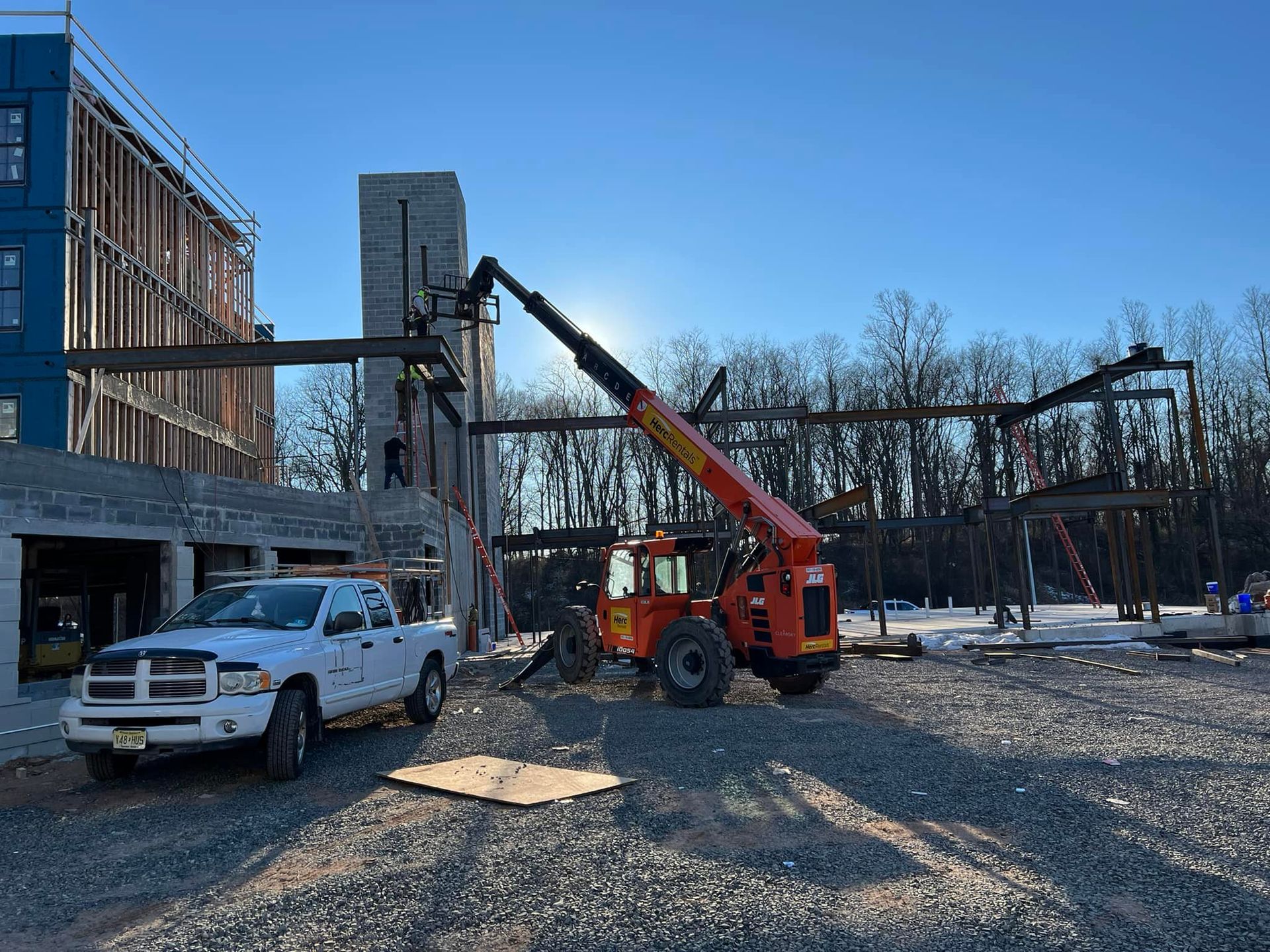 A truck and a crane are parked in front of a building under construction.