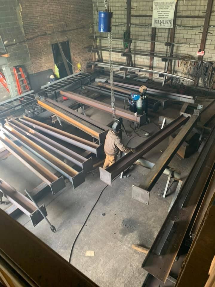 A man is welding a metal structure in a factory.