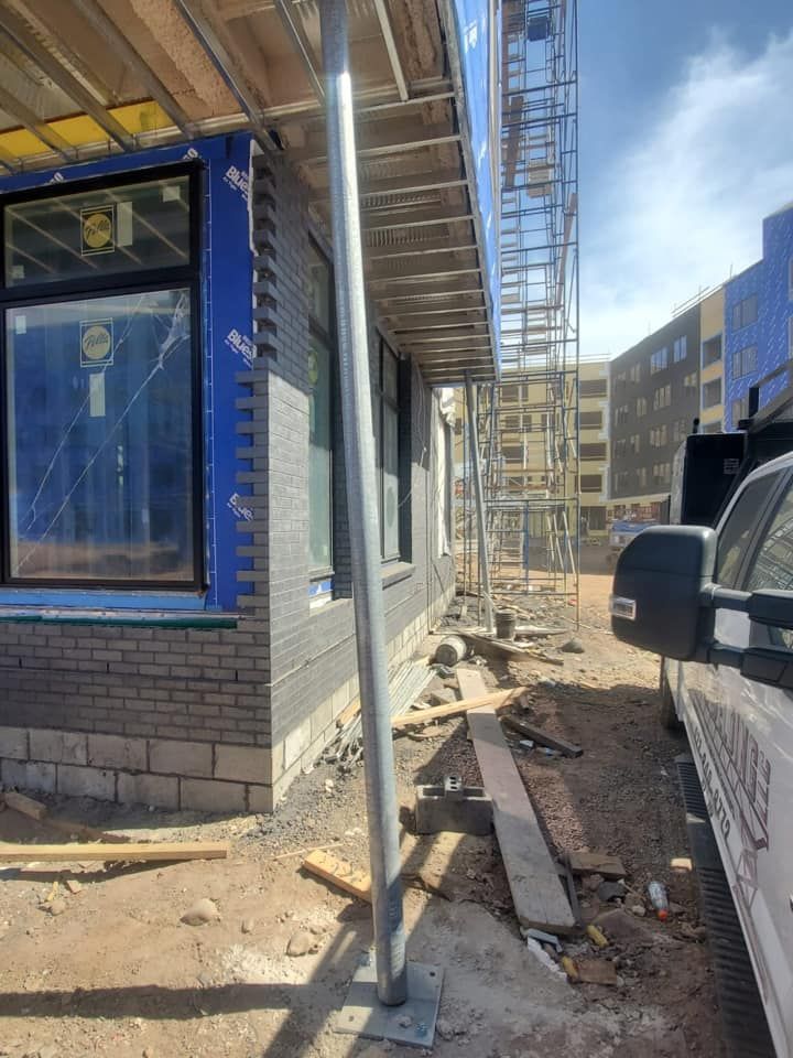 A car is parked in front of a building under construction.