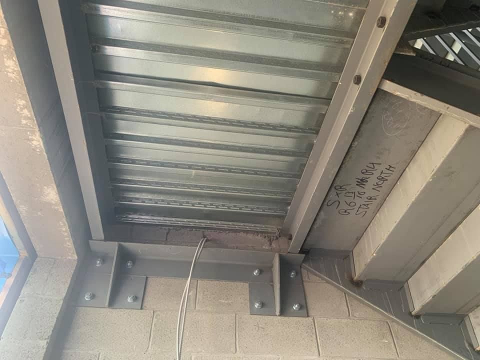 A close up of a metal roof with a brick wall in the background.