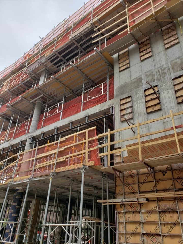 A large building under construction with scaffolding and a wooden railing.