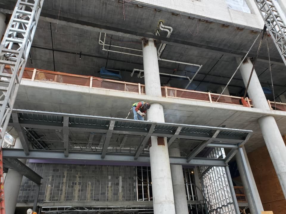A man is welding a metal structure on top of a building under construction