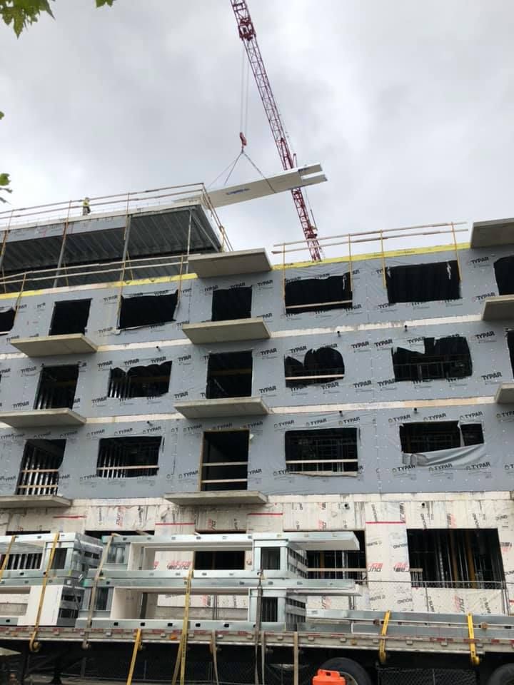 A large building under construction with a crane lifting a beam