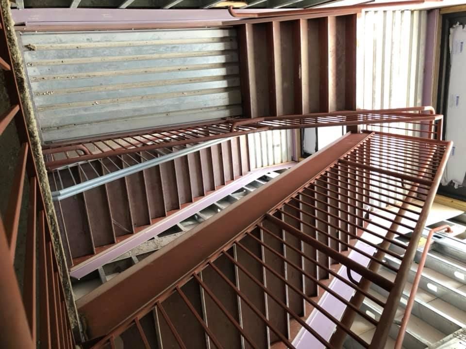 A staircase with a metal railing is going up and down in a building.