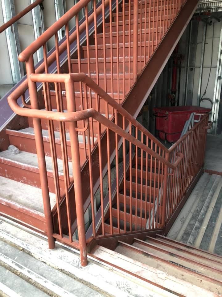 A set of stairs with a red railing going up and down.