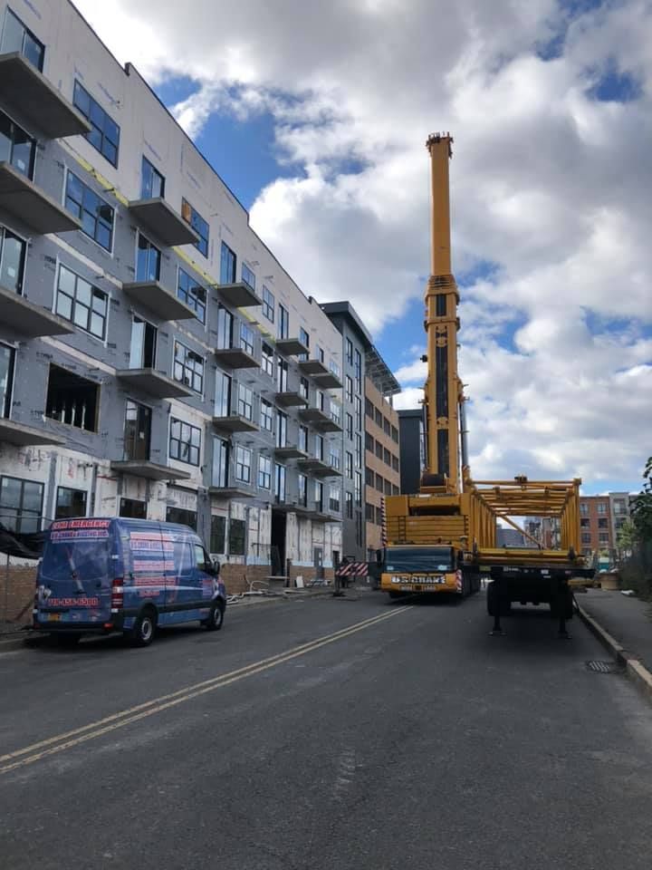 A large yellow crane is parked in front of a building