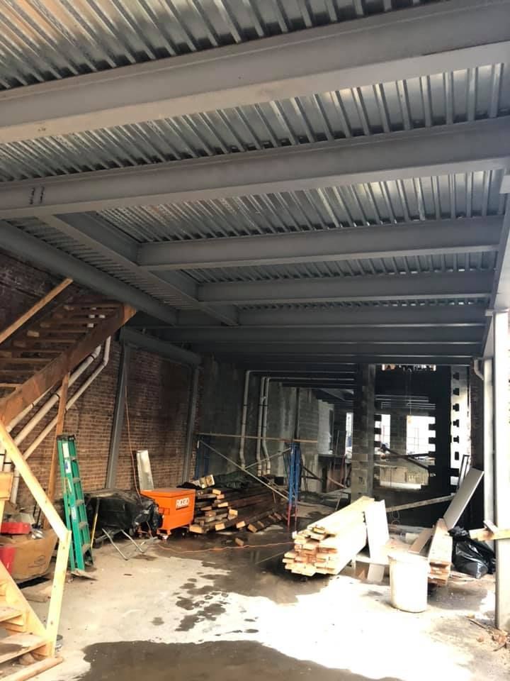 A building under construction with a metal roof and stairs.