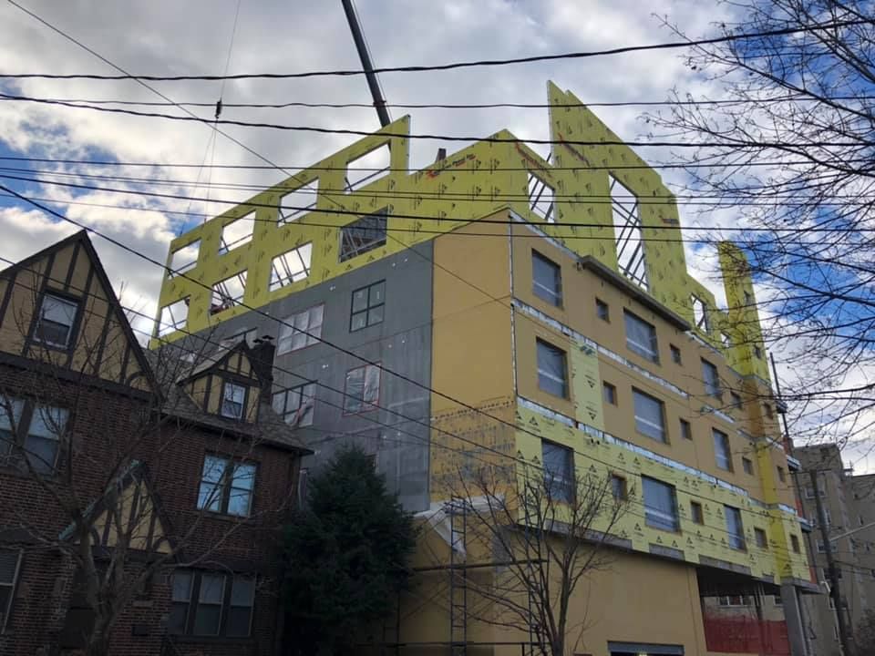 A large yellow building is being built in a city.