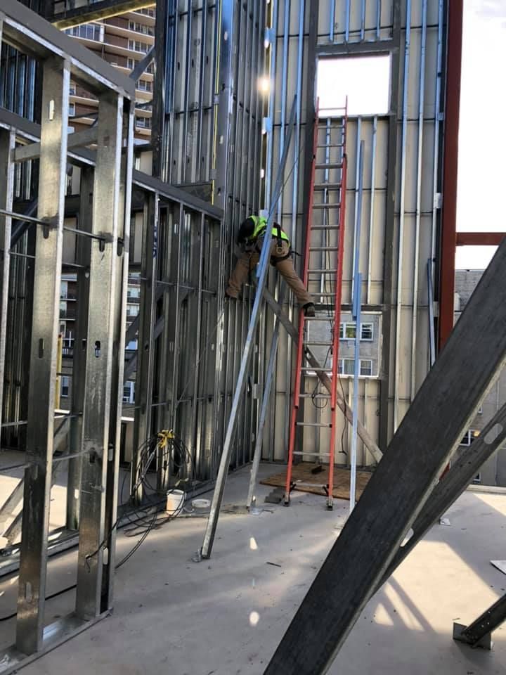 A man is standing on a ladder in a building under construction.