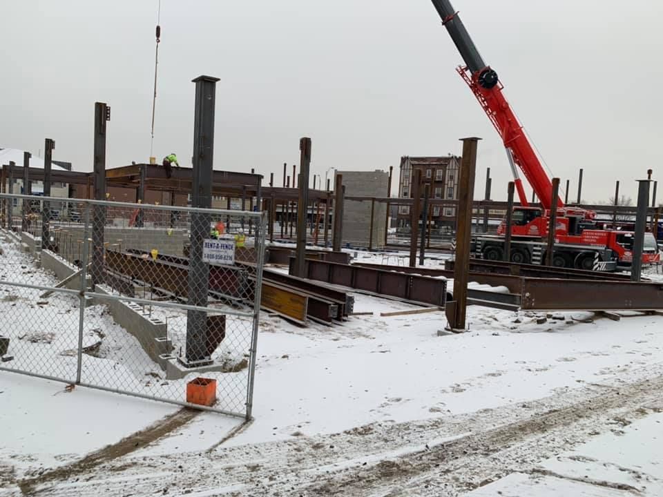 A construction site with a red crane in the snow