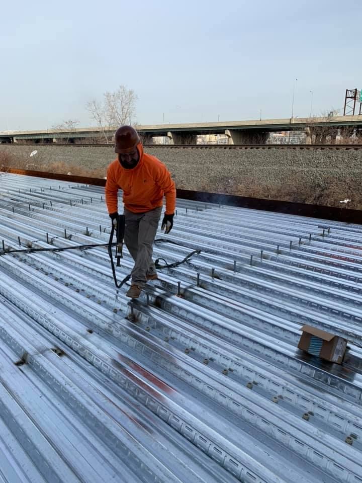 A man is spraying a metal roof with a hose.