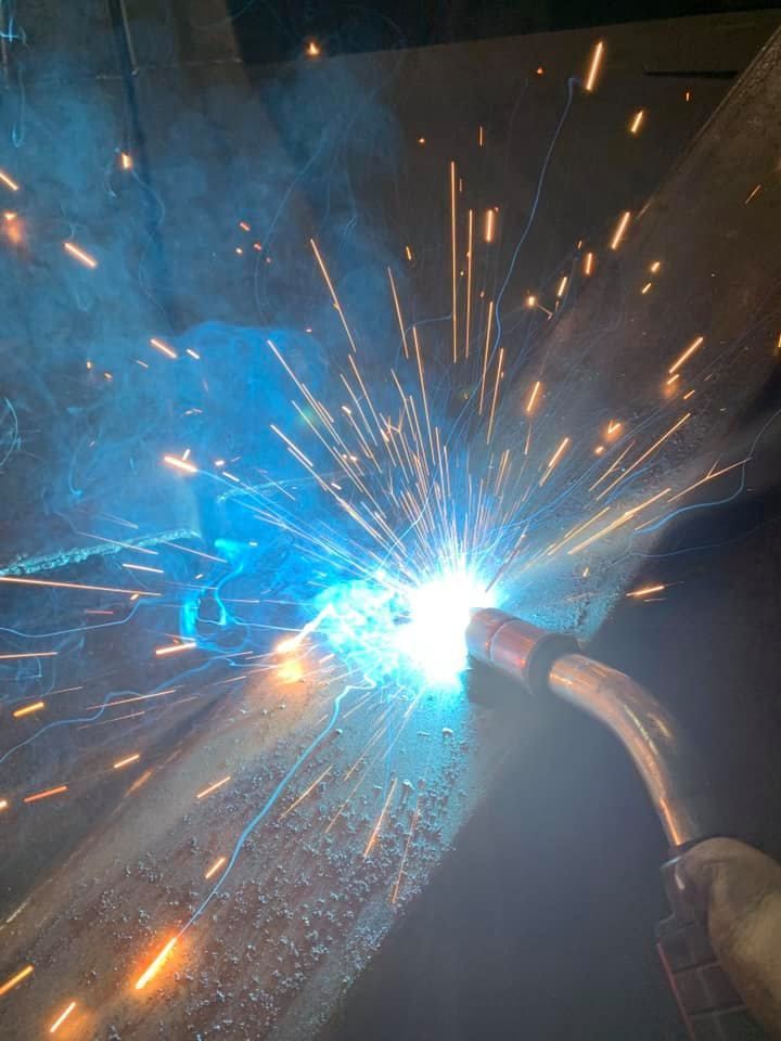 A person is welding a piece of metal with sparks coming out of it.