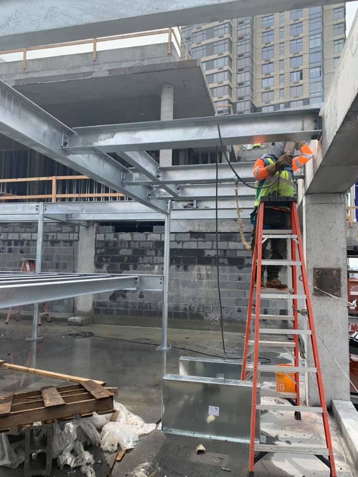 A man is sitting on a ladder working on a metal structure.