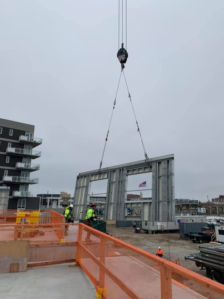 A crane is lifting a large piece of metal on a construction site