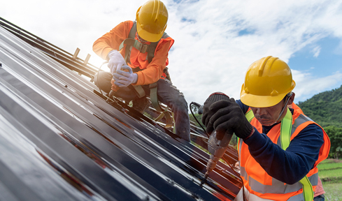 Two construction workers are working on a roof.