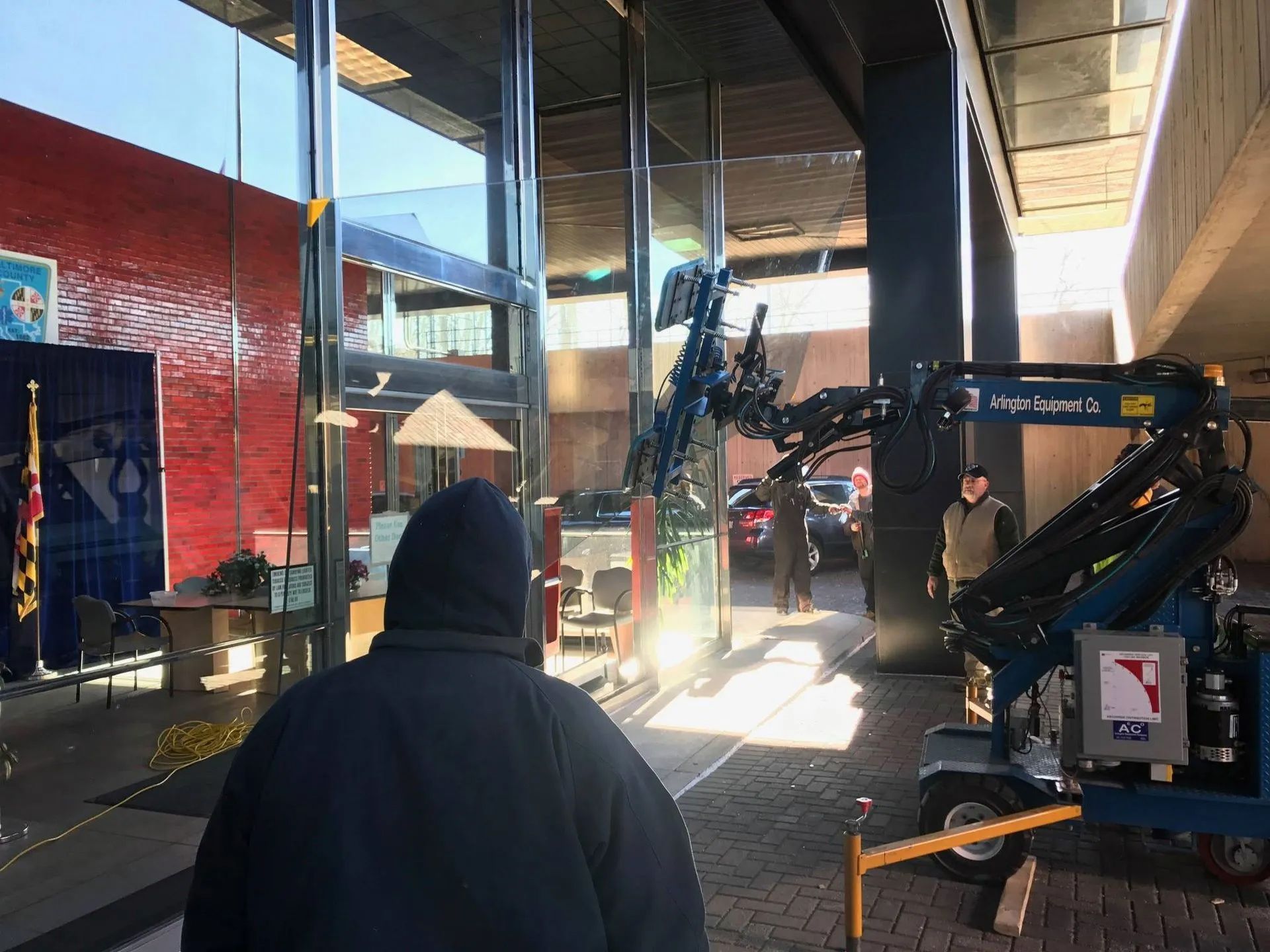 A man in a hooded jacket is standing in front of a building.