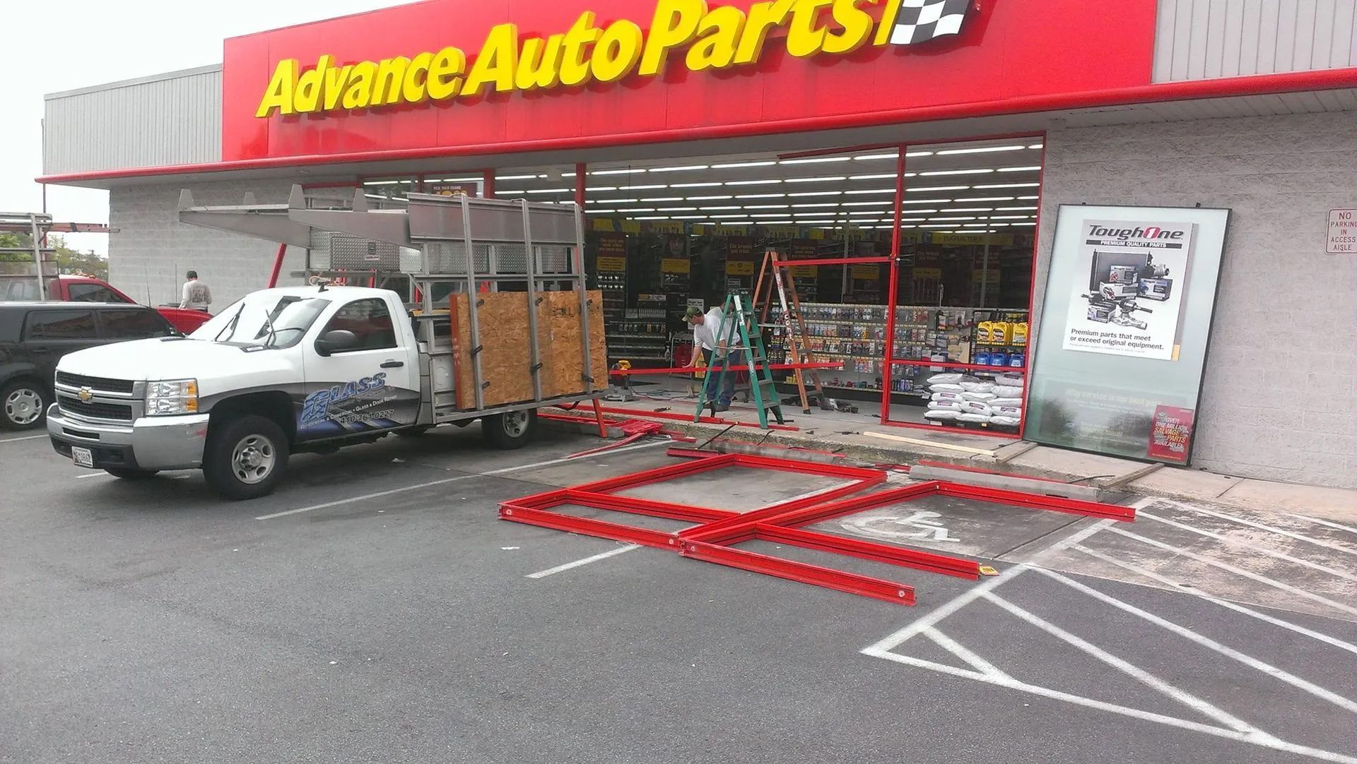 A white truck is parked in front of an advance auto parts store.
