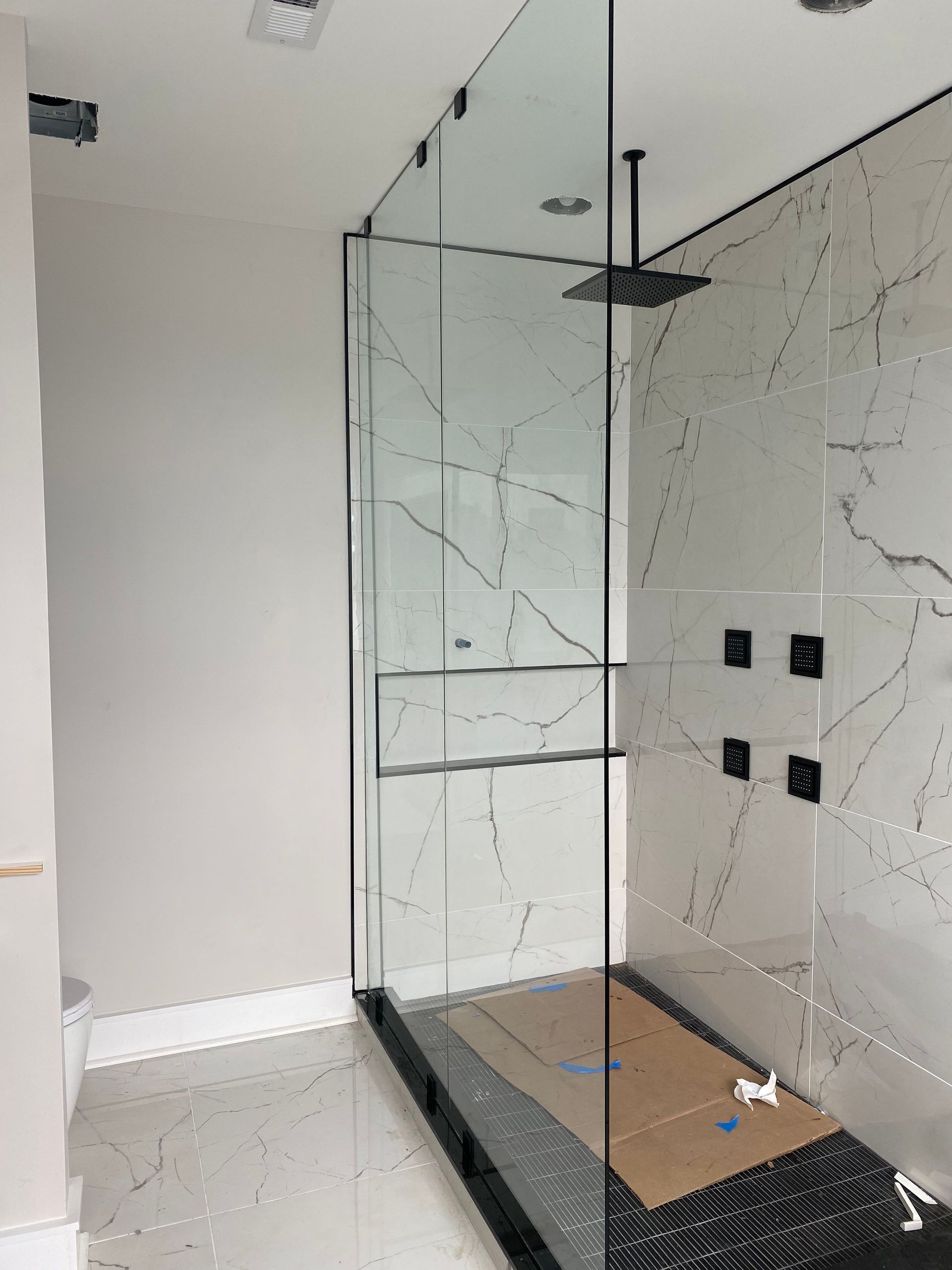 A bathroom with a walk in shower and a ceiling fan.