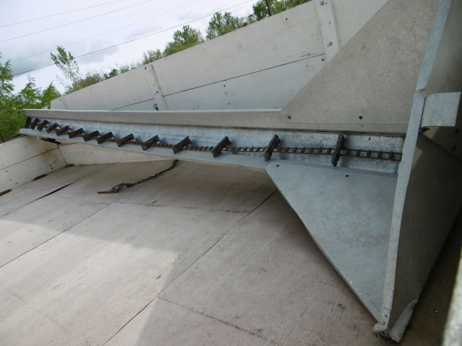 A side view of a metal chain assembly attached to a gray concrete structure outdoors.
