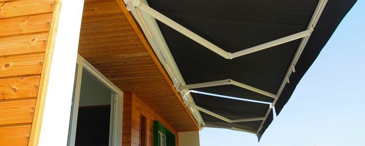 A black awning attached to a wooden building with a clear blue sky in the background.