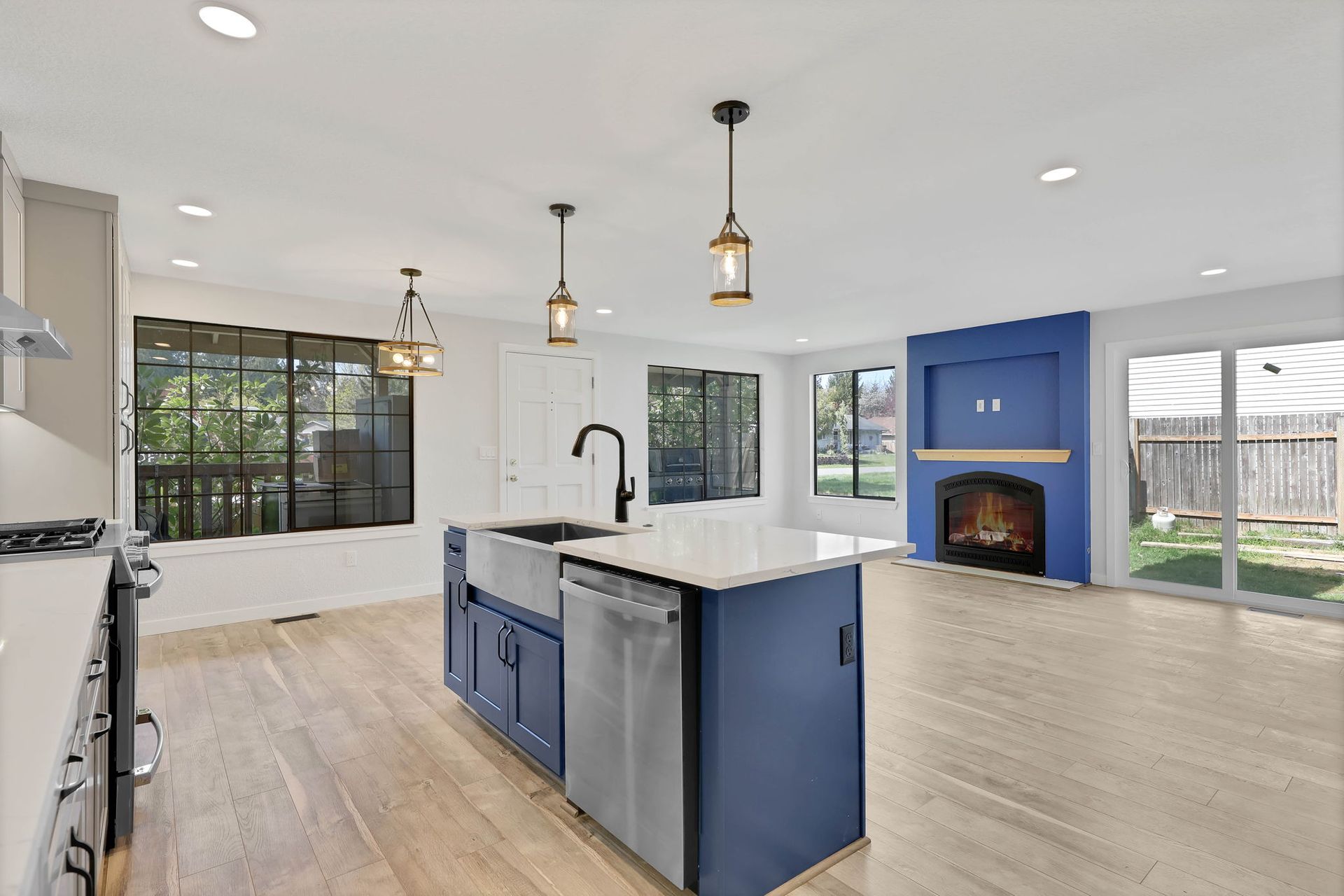 Modern kitchen with blue island, stainless steel appliances, and a blue fireplace wall.