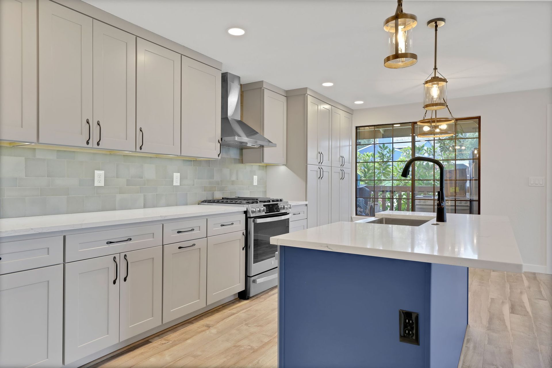 Modern kitchen with gray cabinets, blue island, and black faucet.