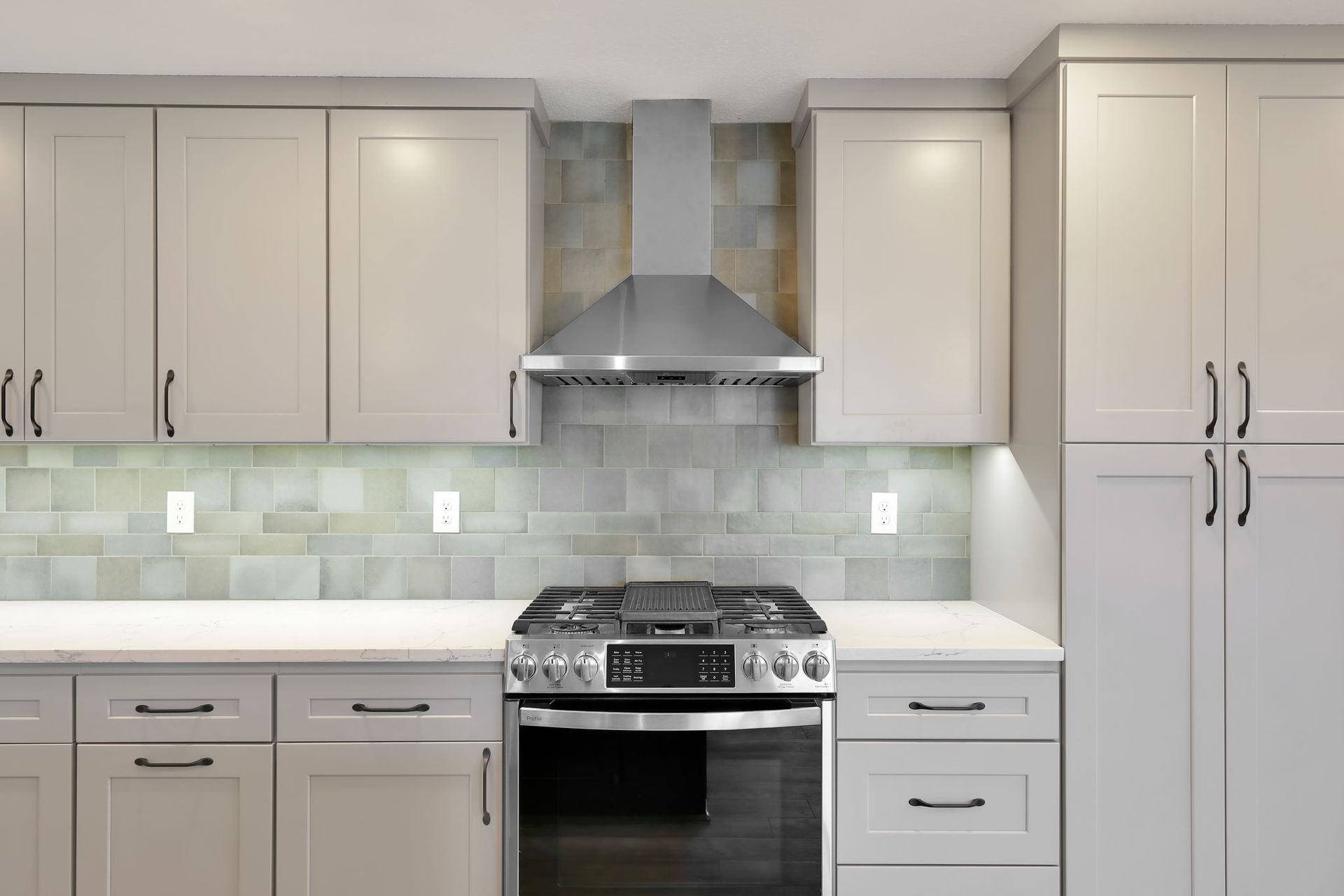 Modern kitchen with gray cabinets, stainless steel appliances, and a gray tile backsplash.