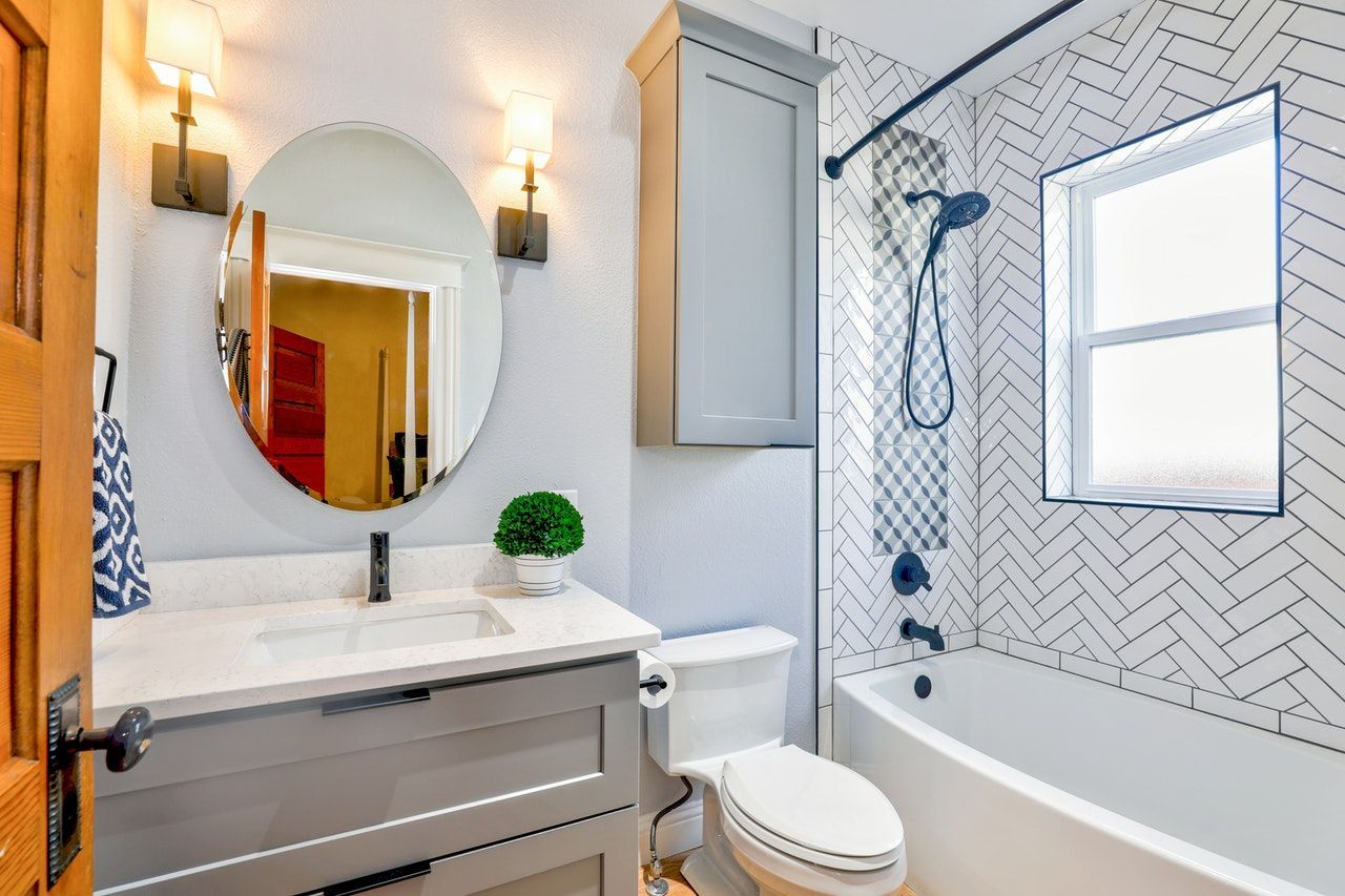 Gray and white renovated bathroom with a vanity, toilet, and bathtub.