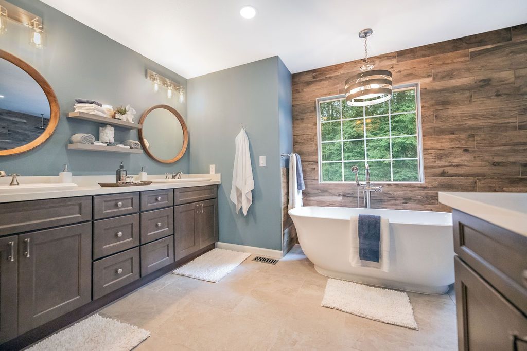 Spacious bathroom with wood accent wall, free-standing tub, double vanity, and large window.