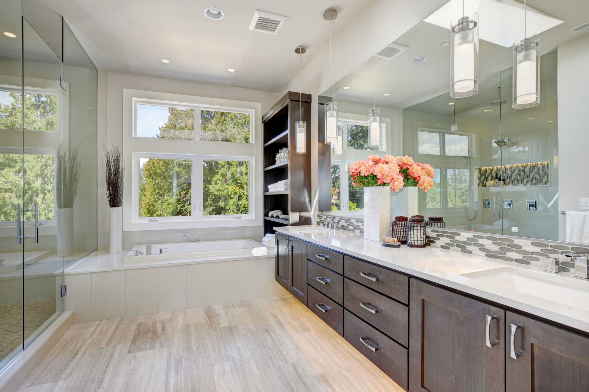Spacious modern bathroom with a large window, glass shower, dark wood cabinets, and a white countertop.
