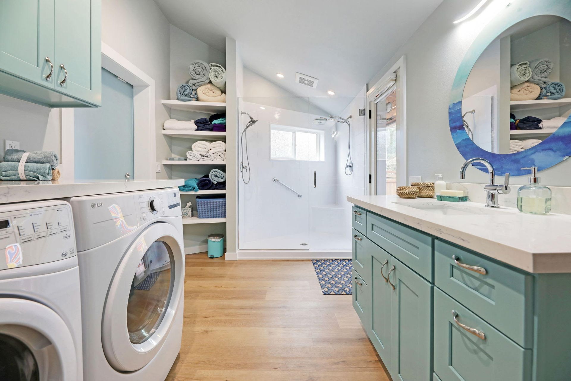 Laundry room with turquoise cabinets, washer/dryer, and open shelving with towels.