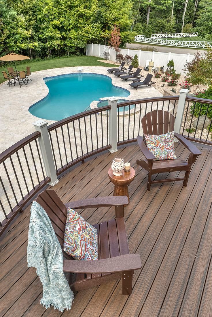 Deck with Adirondack chairs, overlooking a pool. Brown deck and chairs, turquoise pool.