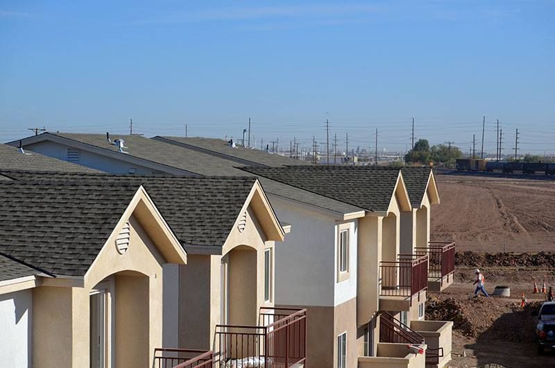 A row of houses with balconies and a blue sky in the background.