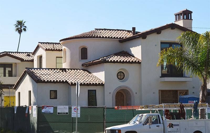 A white truck is parked in front of a large white house