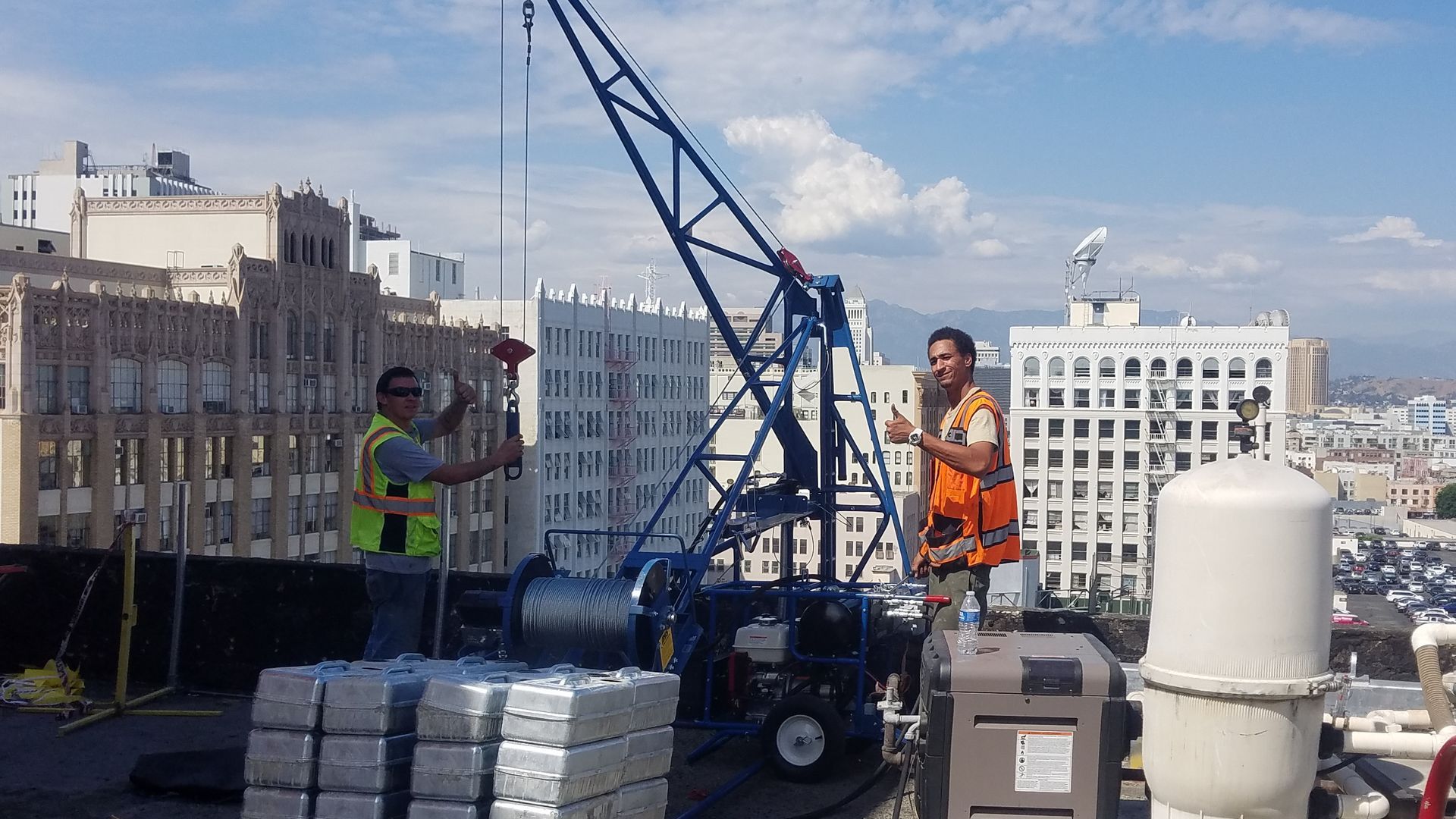 Two men are working on a crane on top of a building.