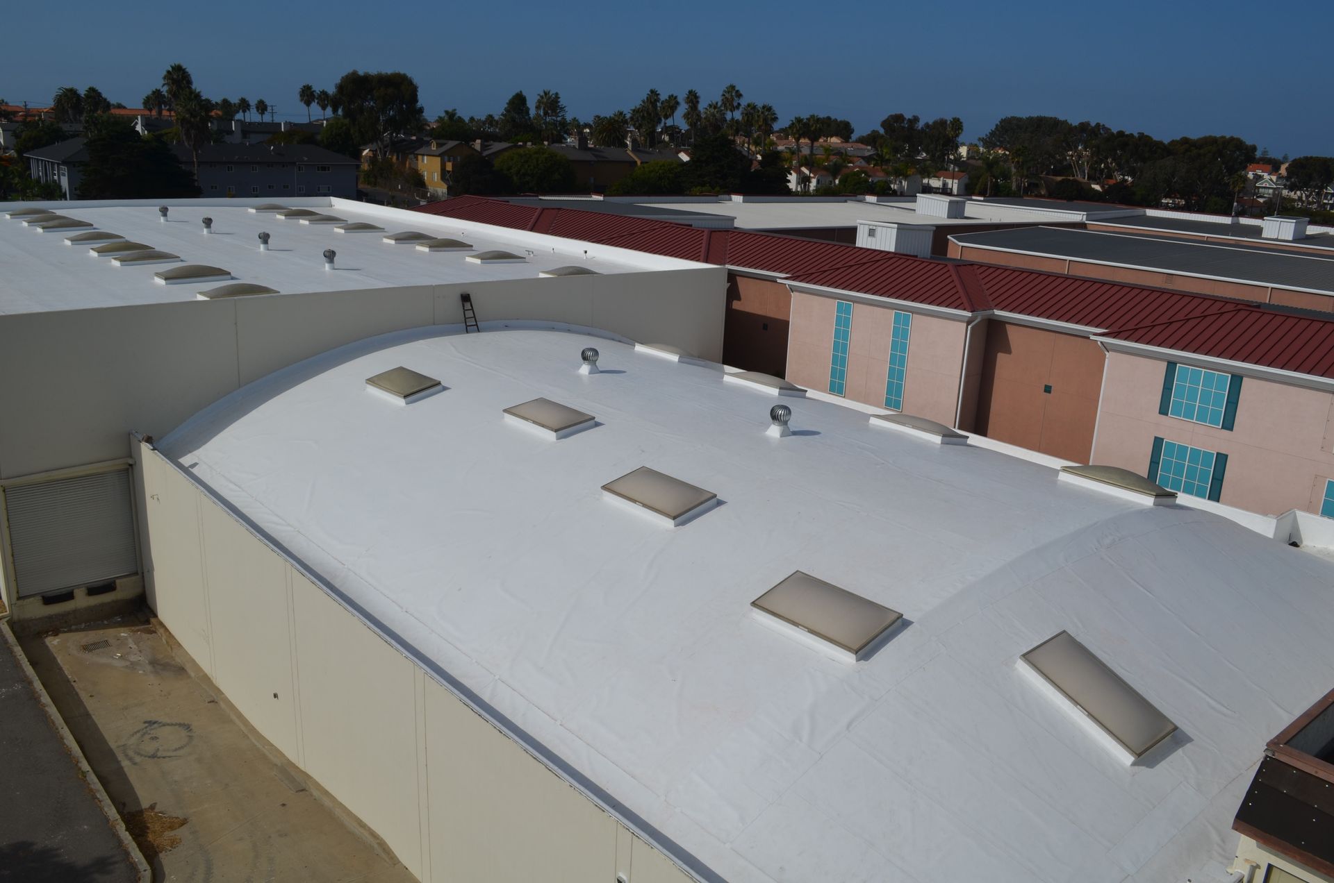 An aerial view of a building with a white roof and skylights