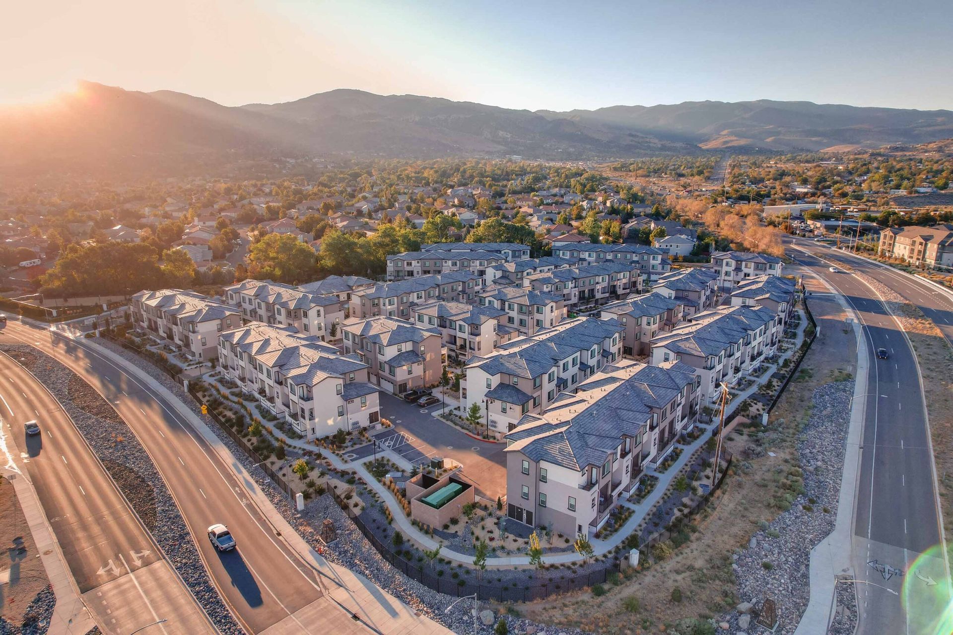 An aerial view of a residential area with a highway and mountains in the background.